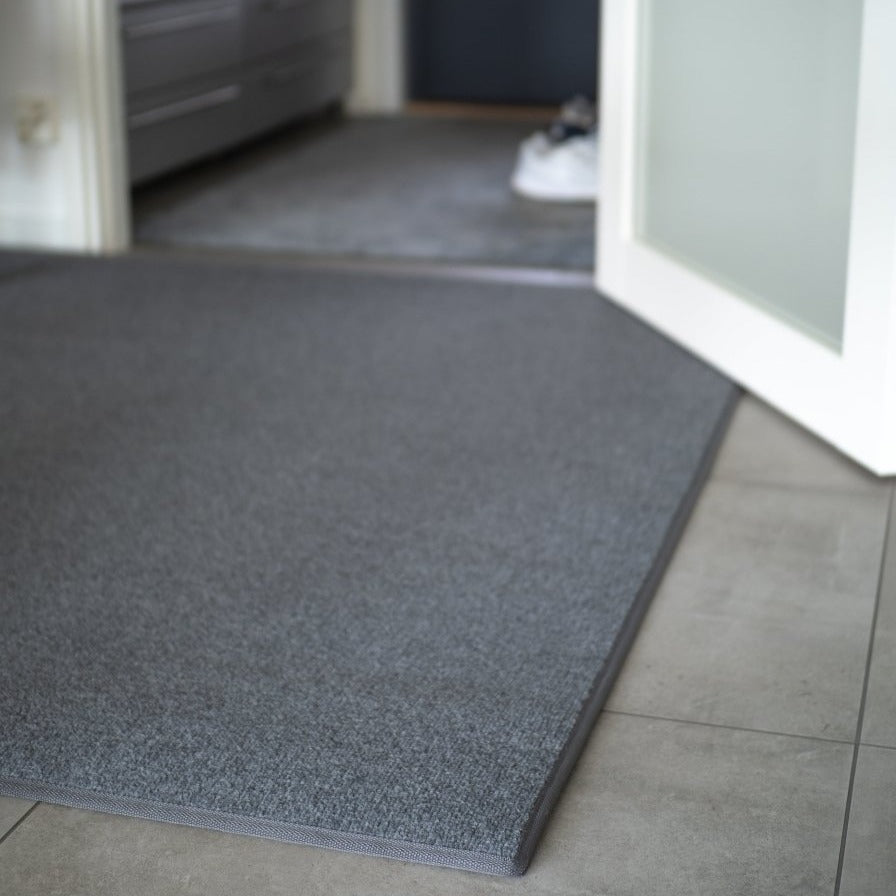 Keskiharmaa eteisen matto laattalattian päällä.